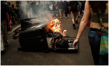 Photographie d'une poubelle en feu lors d'une manifestation